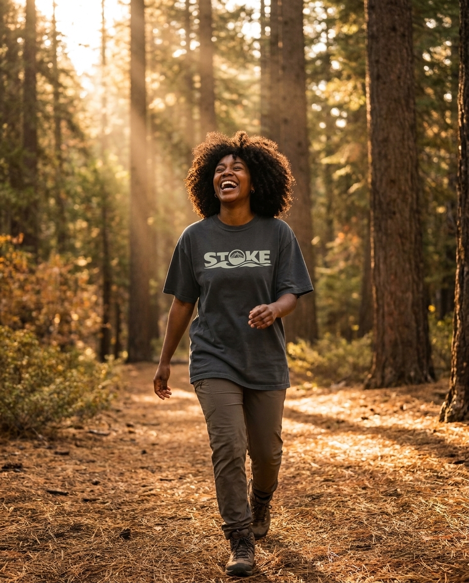 Woman hiking sunlit woods in the unisex STOKE Heavyweight Trail Tee in Faded Black